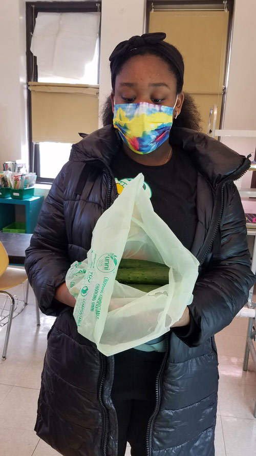 PS118 student holding a bag of cucumbers ready for donation.